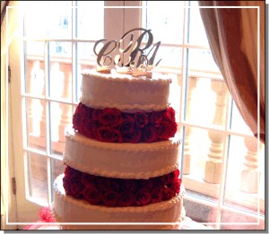 Mirrored monogram cake topper on a wedding cake with alternating tiers of cake and flowers